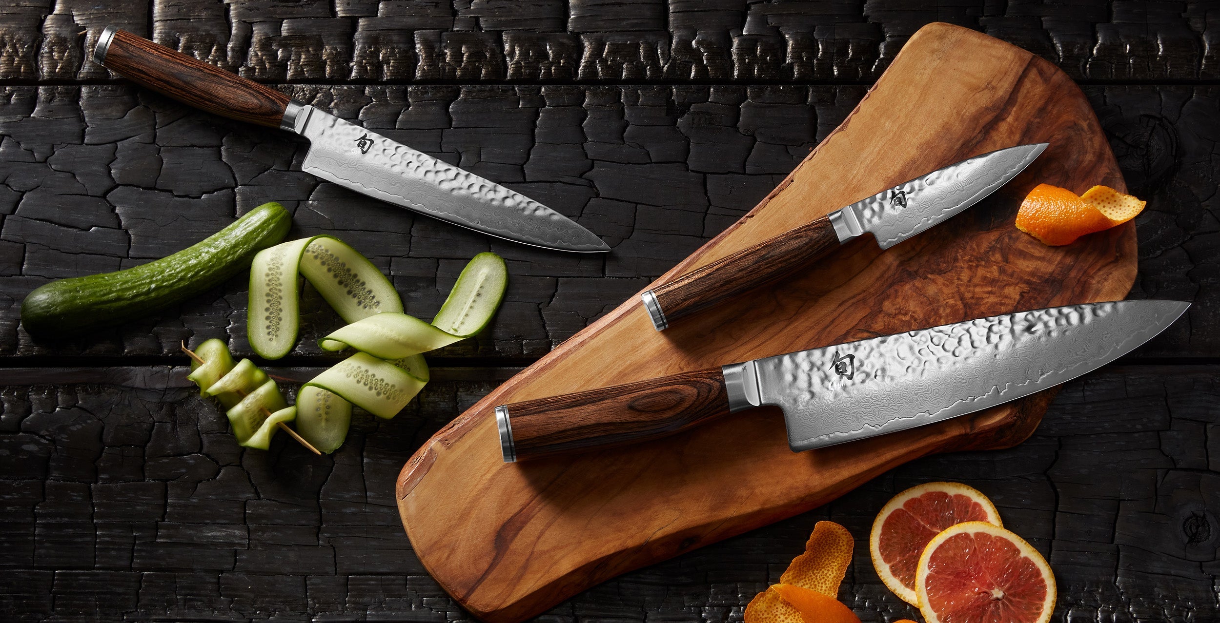 Three Shun Premier knives with hammered Damascus blades on an olive wood cutting board